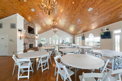 Spacious common area with round tables and chandelier.