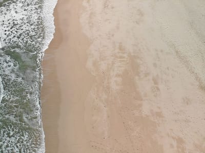 Aerial view of a sandy beach and ocean waves.