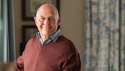 Smiling elderly man in a cozy indoor setting.
