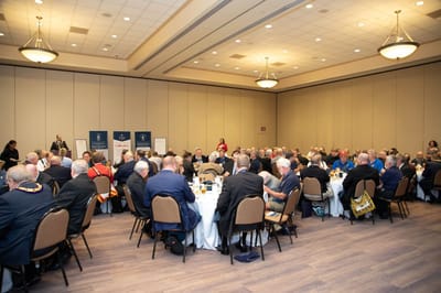 Large gathering in a banquet hall with attendees dining.