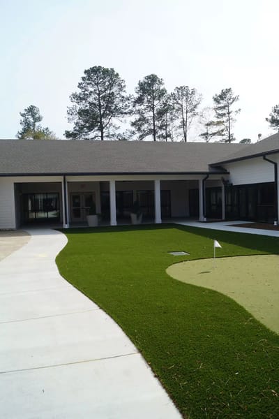 Outdoor putting green with landscaping and building exterior.