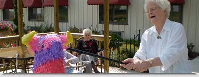 Senior woman hitting a colorful piñata outdoors.