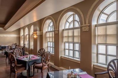 Elegant dining area with arched windows and tables.