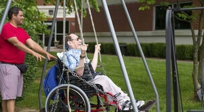 Resident enjoying a swing with staff assistance.