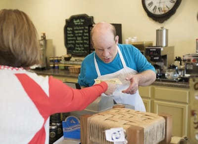 A resident and staff member interacting in a kitchen.