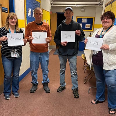 Staff holding signs with an encouraging message