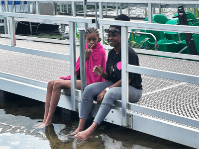 Two children relaxing by the water on a dock.