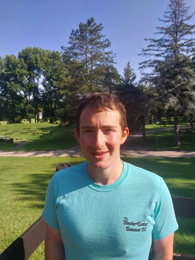 Smiling man in a turquoise shirt outdoors