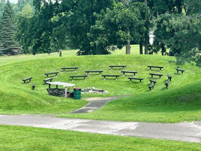 An outdoor gathering area with benches arranged around a fire pit.