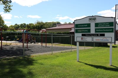 Playground area with signage and grassy space.