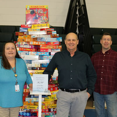 Staff members posing near a food donation display.