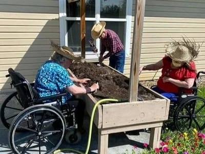 Residents gardening outdoors in raised boxes.