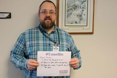 Man holding a sign with reasons to give