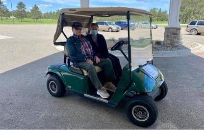 Resident and staff member in a golf cart