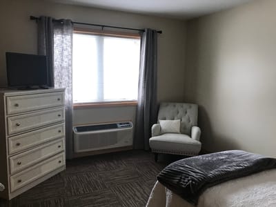 Cozy resident room with a bed and chair.