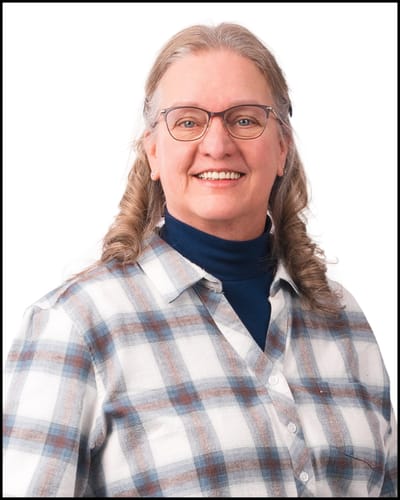 Staff member smiling in a plaid shirt
