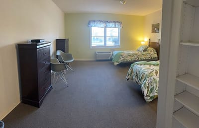 Twin bedroom with floral bedding and seating area.