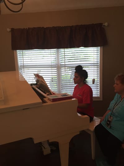 Resident and staff member at a piano