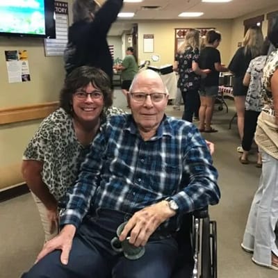 A senior resident smiling with staff member in a common area.