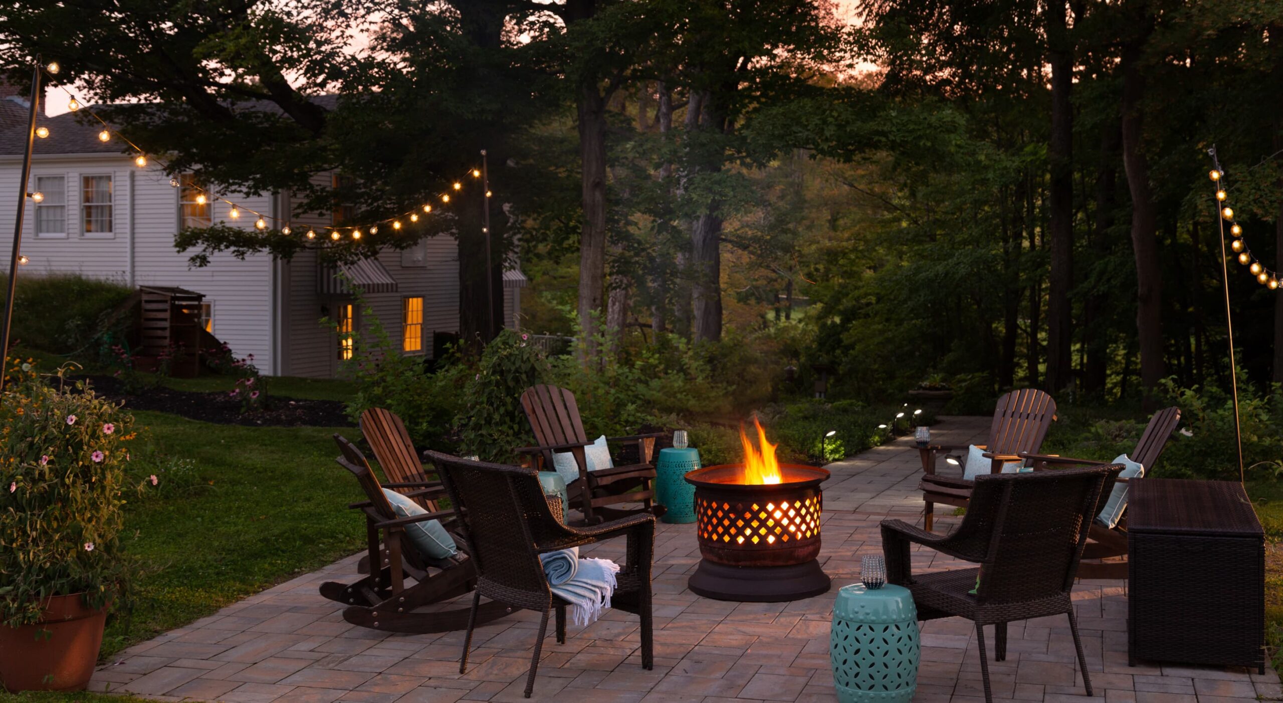 Outdoor seating area with a fire pit and string lights.