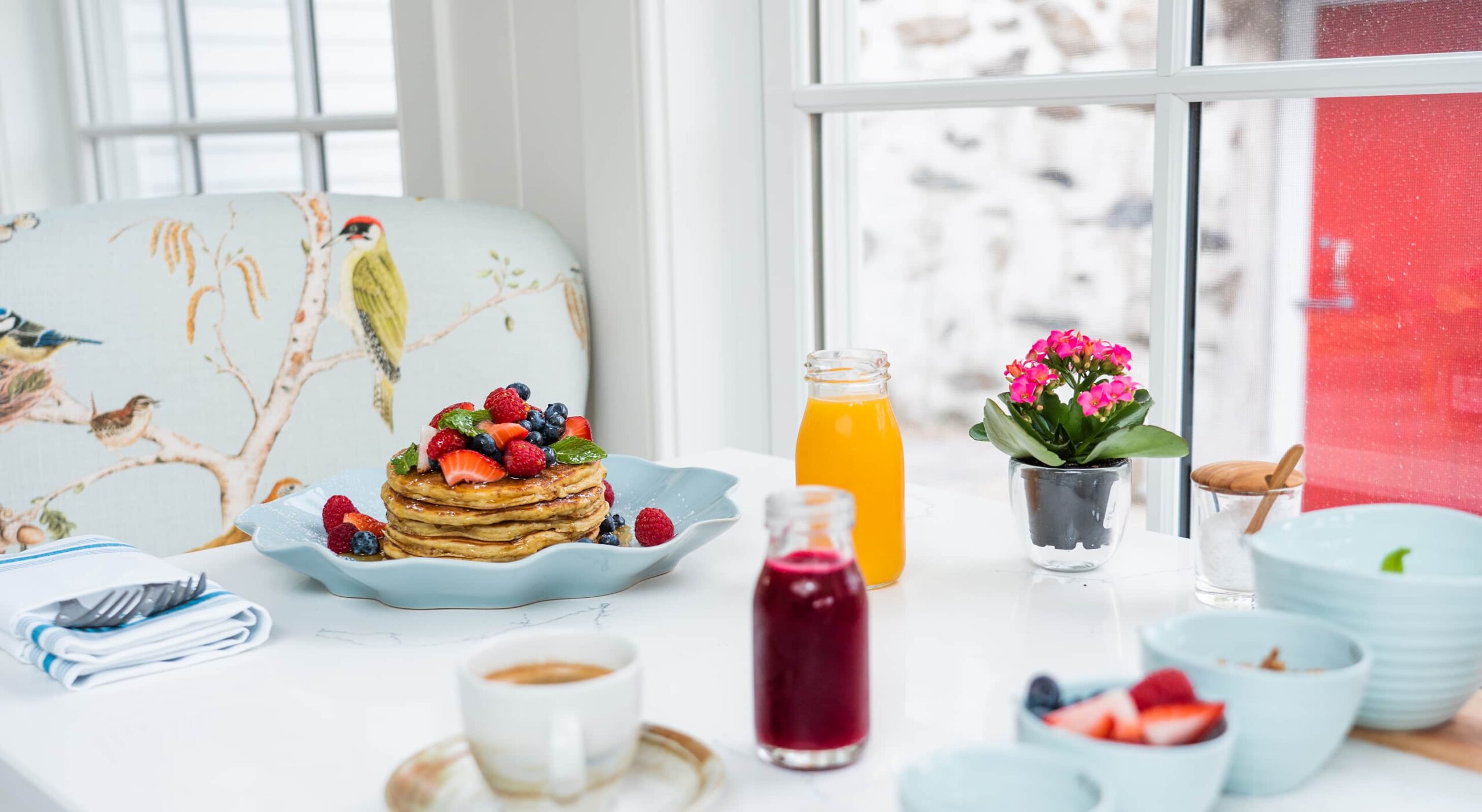 Breakfast with pancakes, fruit, and beverages on a table