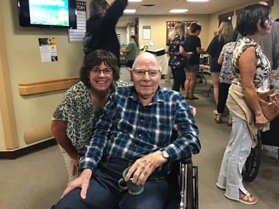 Resident and staff member smiling in a common area.