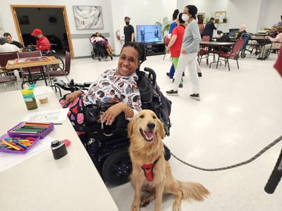 Resident smiling with therapy dog during an activity