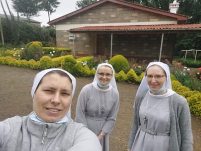 Three sisters in front of a building and garden.