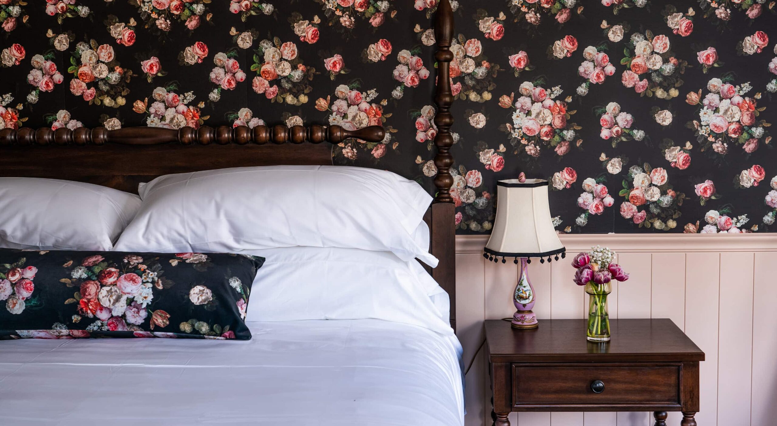 Cozy bedroom with floral wallpaper and bedside lamp.