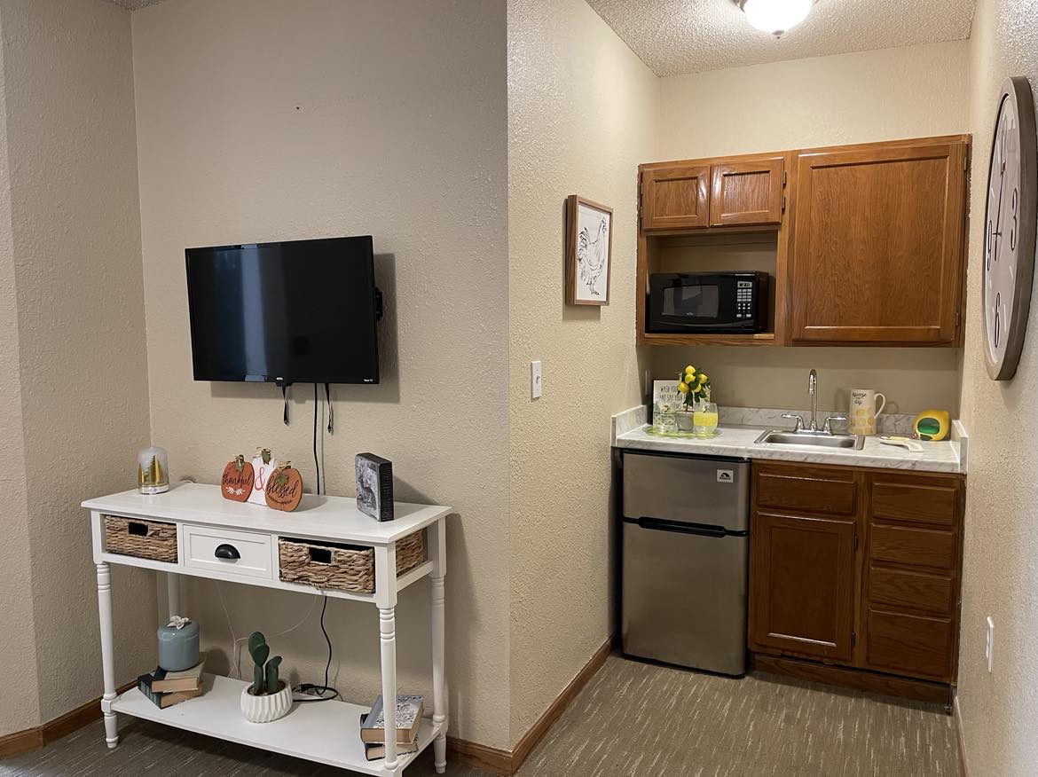 A kitchenette and living area in an assisted living unit.