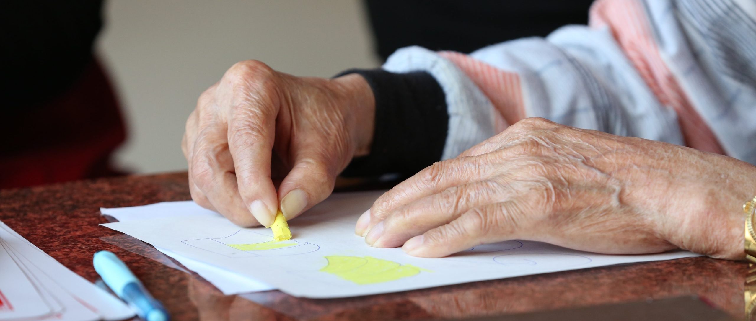 Elderly hands coloring on paper