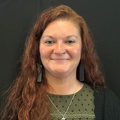 A staff member smiling in front of a black background.