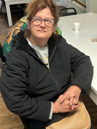 Resident sitting in a common area with a warm expression.