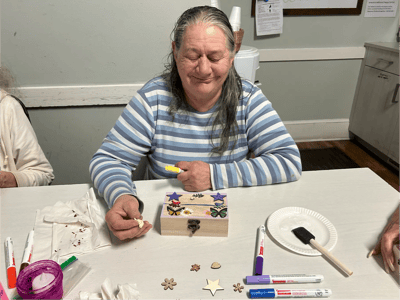 Resident engaged in a craft activity at a table.