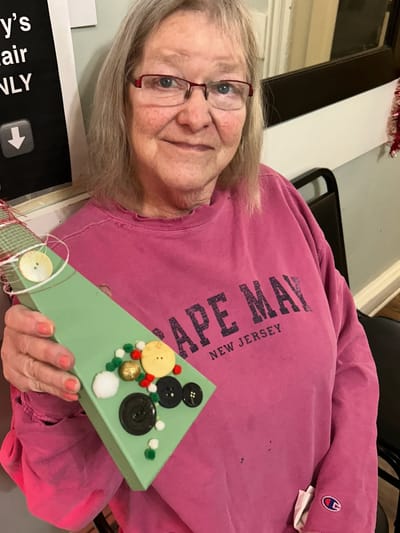 Resident joyfully holding a craft project.