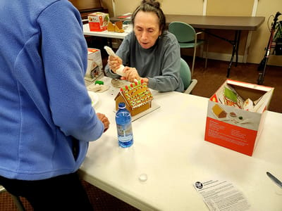 Resident decorating a gingerbread house.