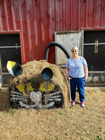 Resident posing with a decorative hay sculpture outside.