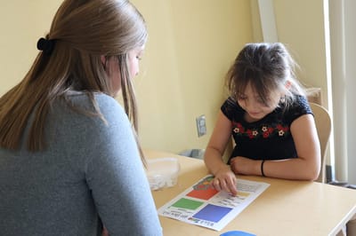 A staff member engaging with a child at a table.