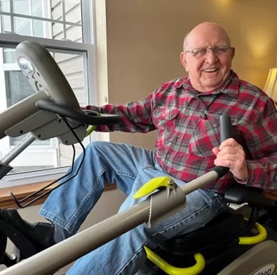 Elderly man using fitness equipment indoors.