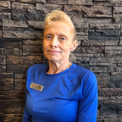 Staff member in a blue shirt against a stone wall