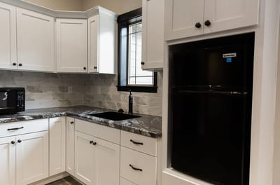 Modern kitchen with white cabinets and black appliances.