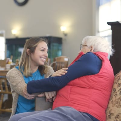 Staff interacting warmly with a resident in a common area.