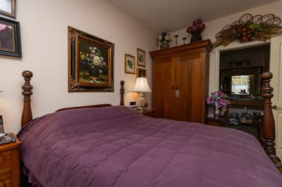 Cozy bedroom with floral artwork and wooden furniture.