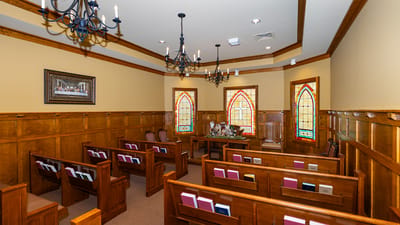Interior chapel with wooden pews and stained glass windows.