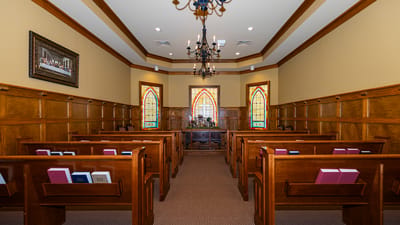 Interior chapel with wooden pews and stained glass windows.