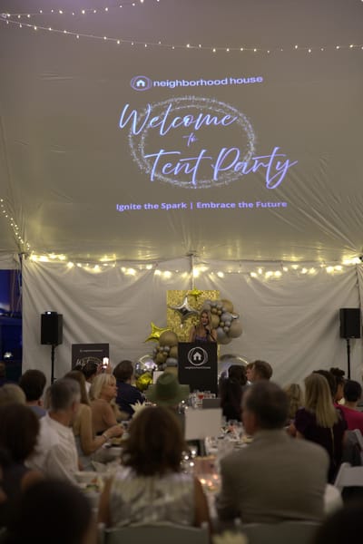 People gathered at a festive event under a tent.
