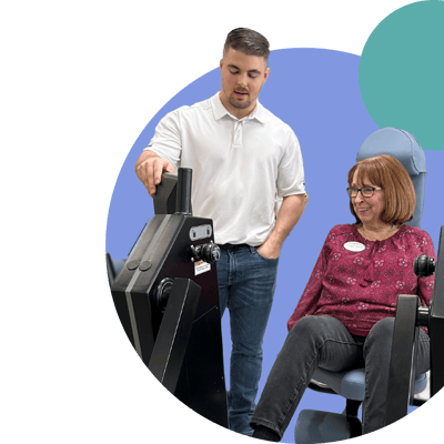 Staff assisting a resident with fitness equipment.