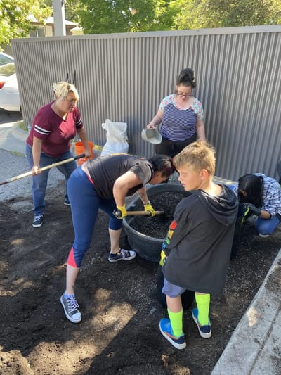 Residents and staff gardening together outdoors.