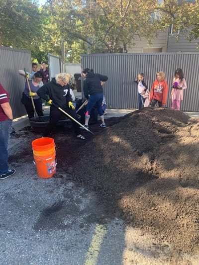 Volunteers working outdoors with soil and shovels.