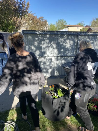 Two people carrying a planter in a garden.